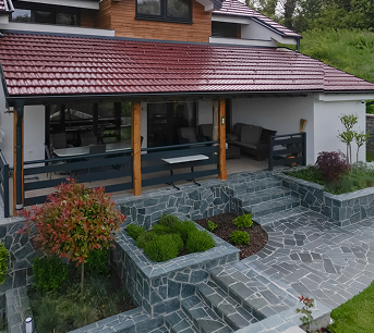 Terrasse aus Naturstein mit Sitzecke am Haus