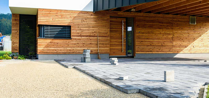 Terrasse aus Betonplatten vor einem Holzhaus