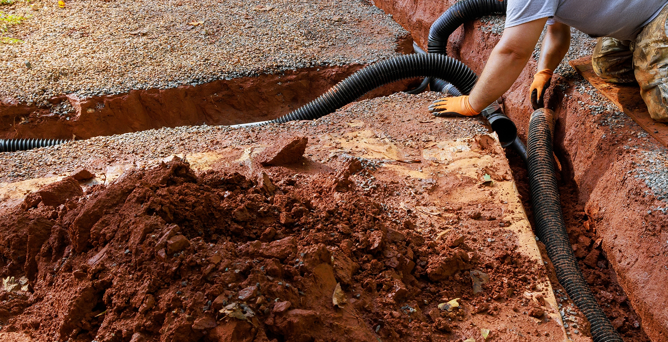 Verlegen eines Drainagerohrs im ausgehobenen Graben