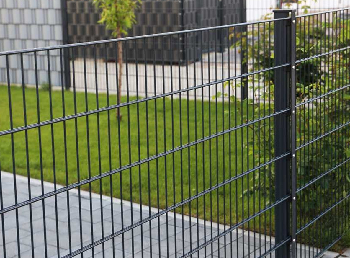 Doppelstabmattenzaun mit Metallpfosten vor einem Garten