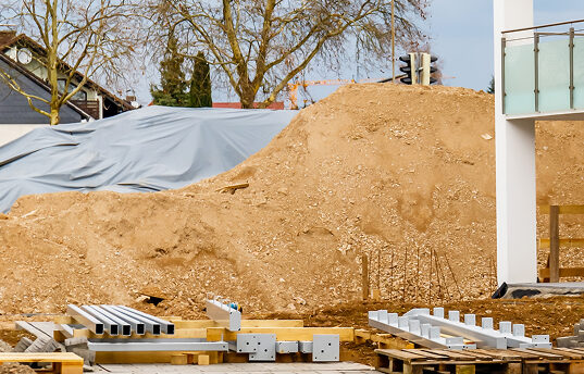 Abgedeckter Sandhaufen auf dem Baustofflager