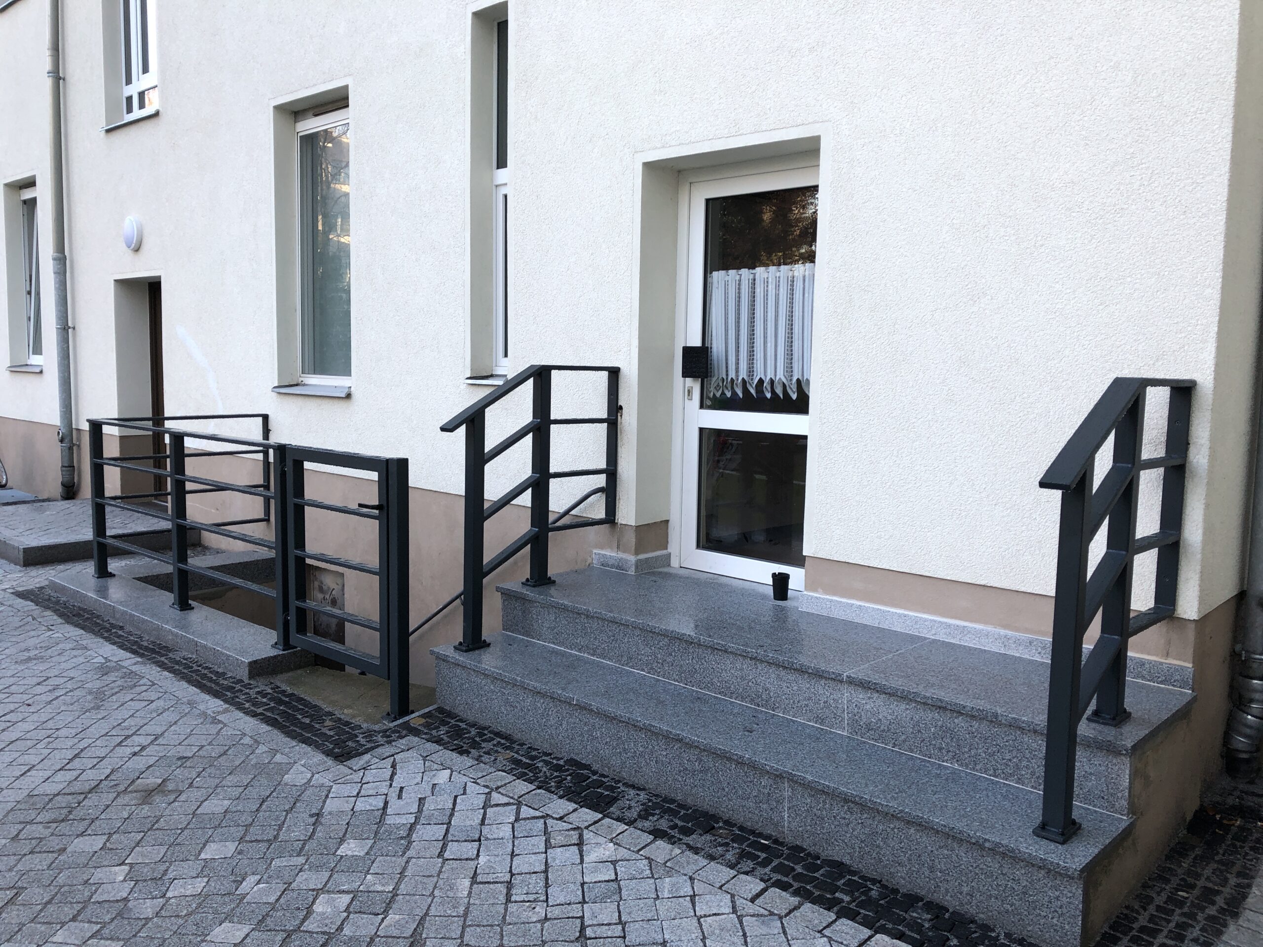 Gepflasterter Hauseingang mit Treppe und Geländer