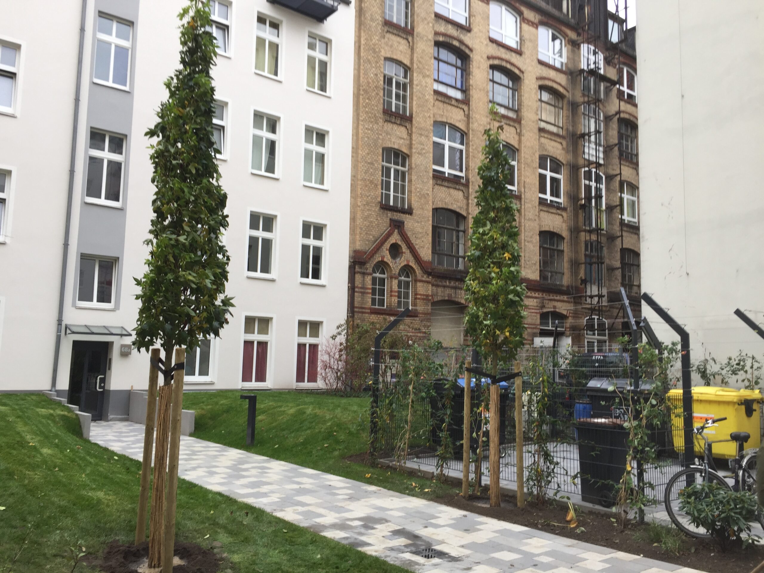 Neu gestalteter Innenhof mit Pflasterwegen und Jungbäumen